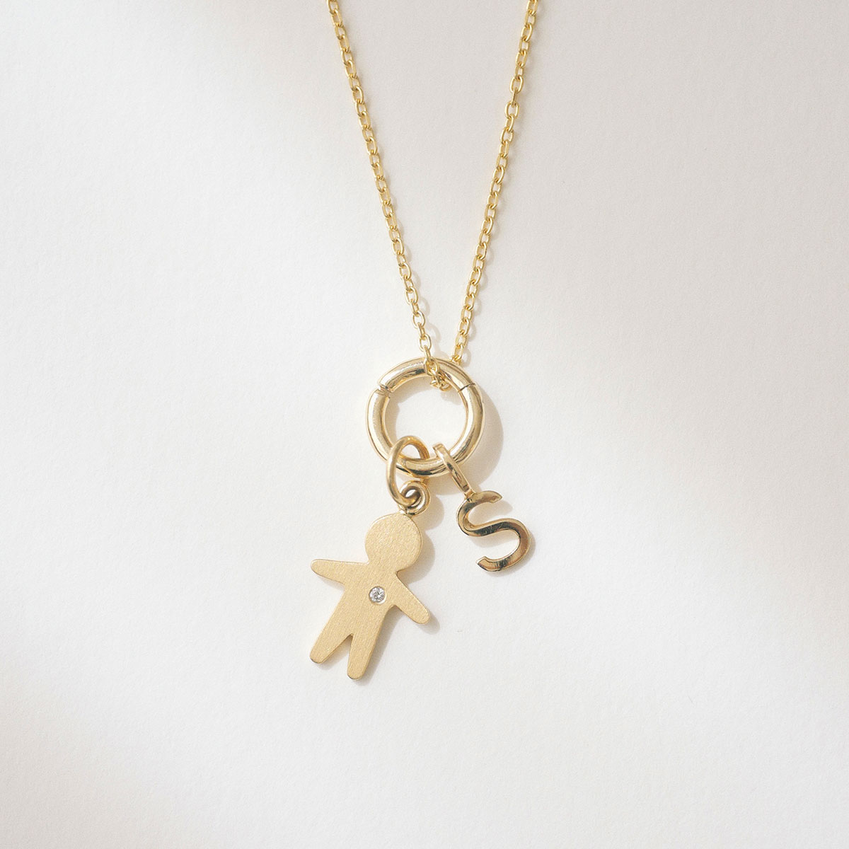 Porta pingente redondo versátil em ouro 18k com pingente filho e pingente letra S pendurados.