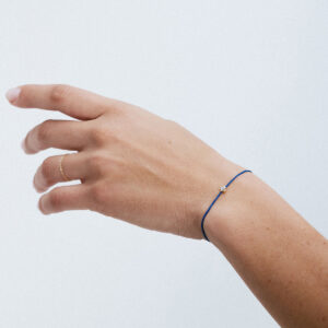 Pulseira com cordão de seda azul e pedra branca safira com detalhes em ouro 18k