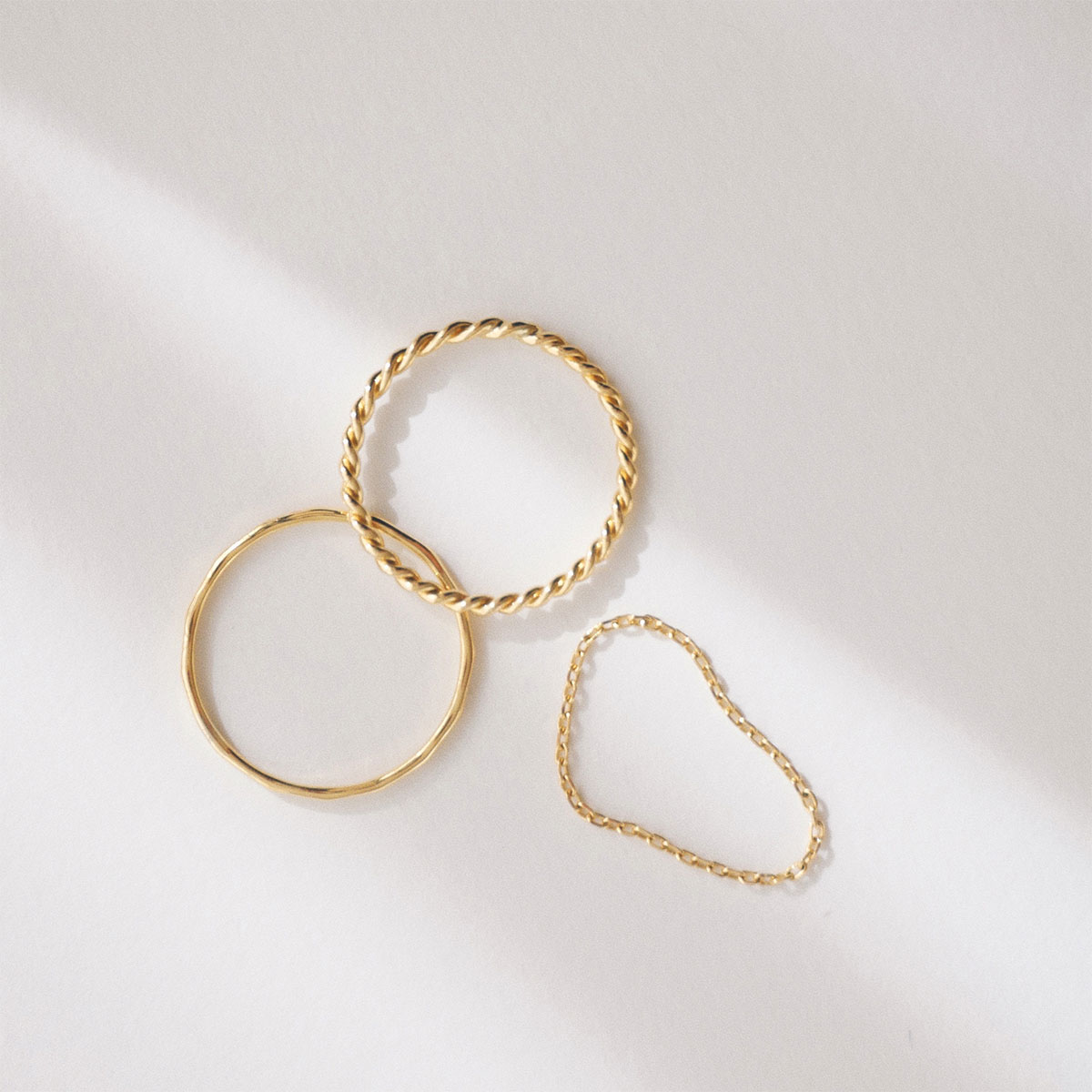 Trio de anéis minimalistas em ouro 18k com texturas diferentes: corrente, torcido e martelado.