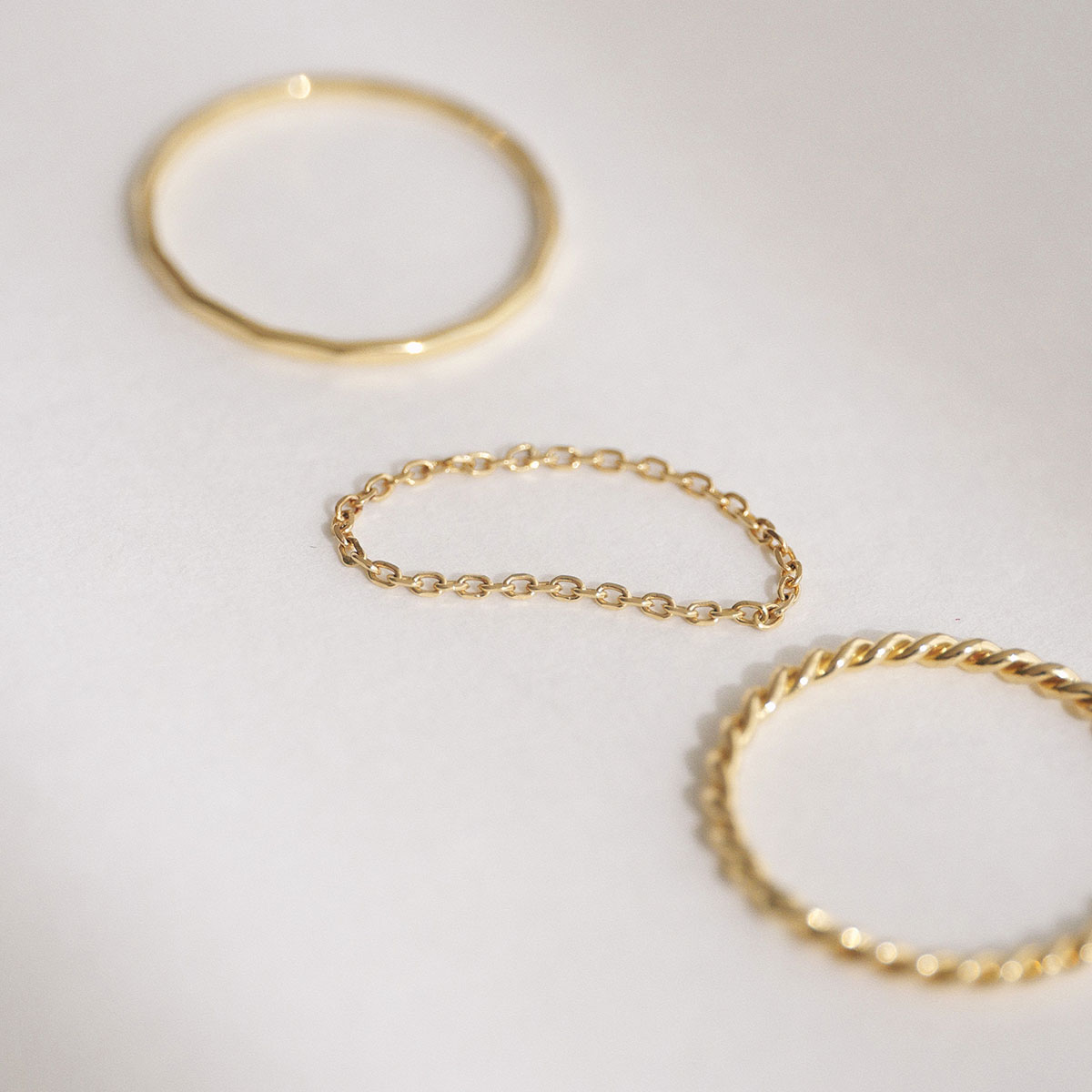 Trio de anéis minimalistas em ouro 18k com texturas diferentes: corrente, torcido e martelado.