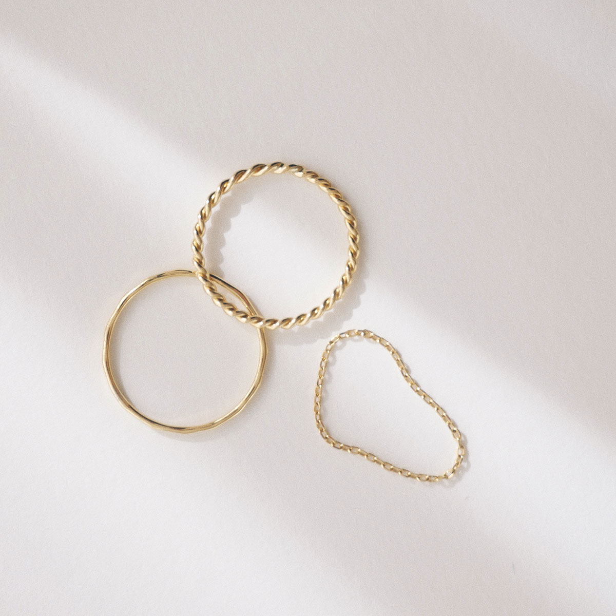Trio de anéis minimalistas em ouro 18k e texturas diferentes: torcido, martelado e corrente.
