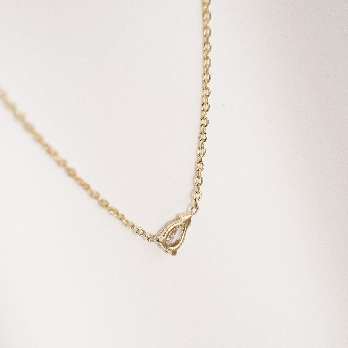 Colar em ouro 18k com diamante em lapidação gota centralizado na corrente. Colar virado para mostrar o acabamento da parte de trás do pingente.