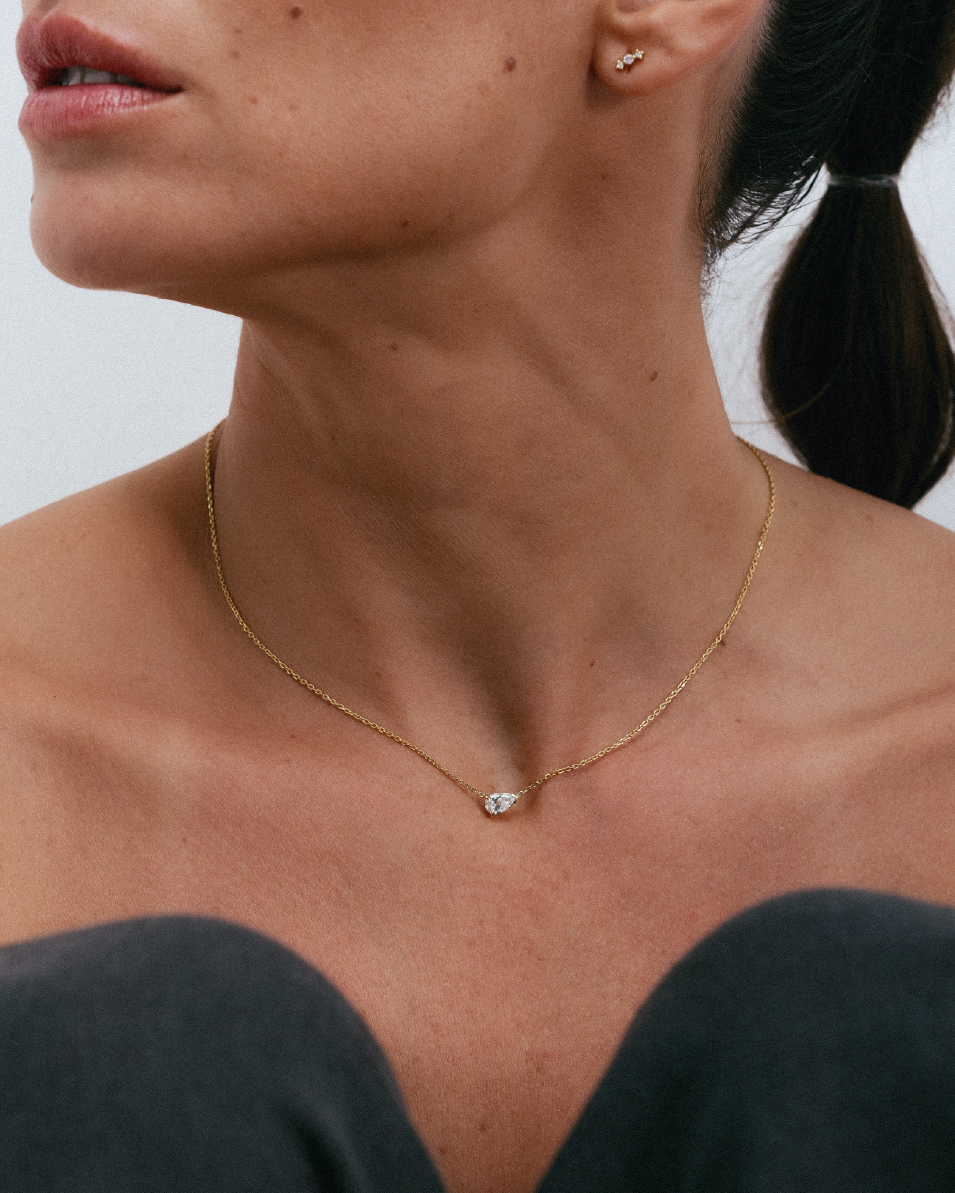 Mulher usando colar delicado em ouro 18k com diamante em formato gota no pescoço