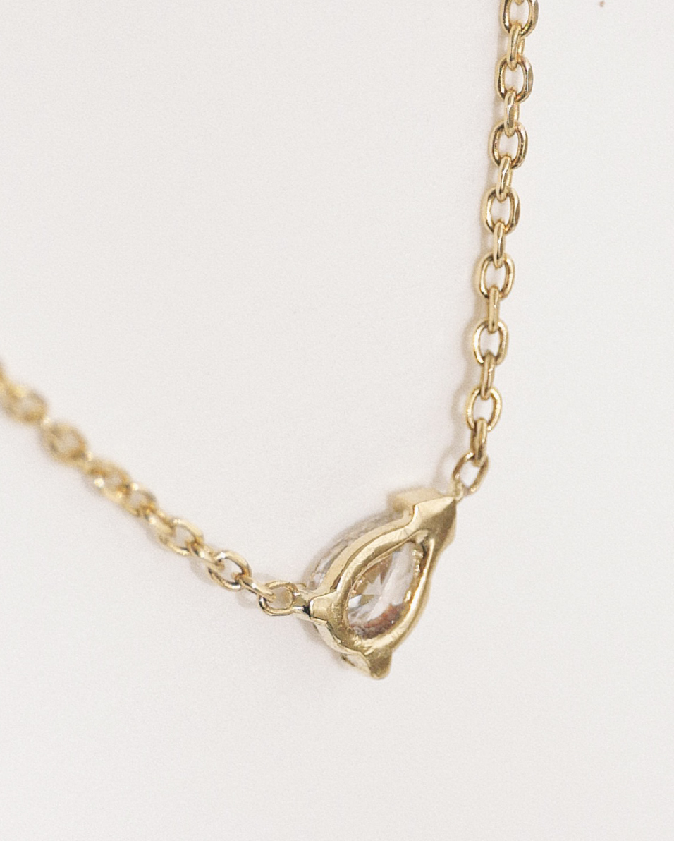 Detalhe de colar em ouro 18k com diamante em formato gota e acabamento delicado