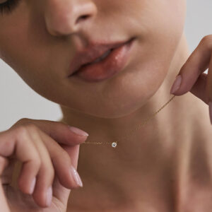 Mulher usando colar solitário em ouro 18k com diamante de 10 pontos.