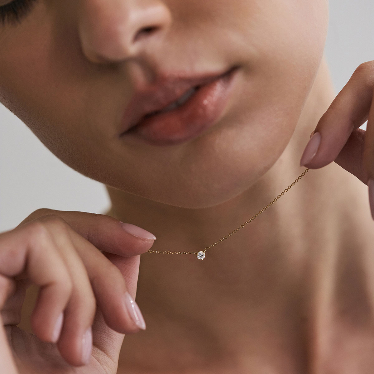 Mulher usando colar solitário em ouro 18k com diamante de 10 pontos.