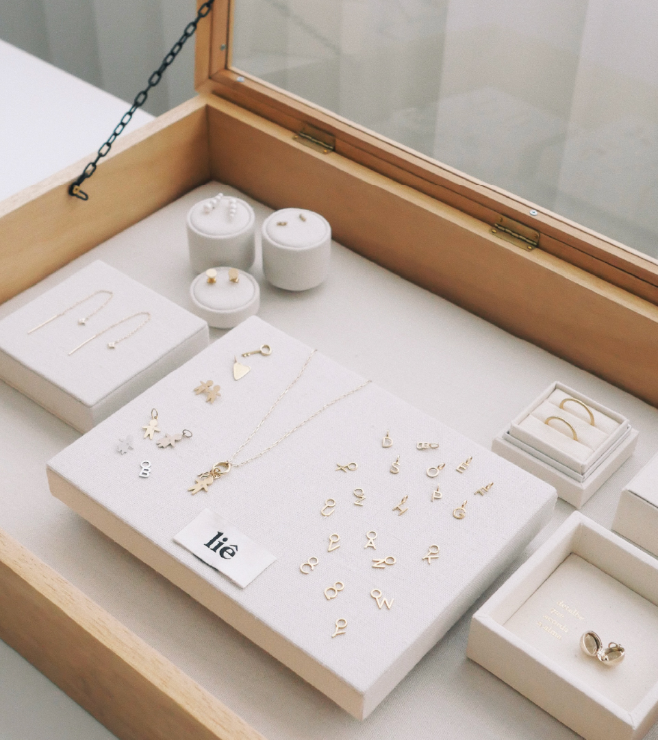 Joias personalizadas em ouro 18k com letras e colares expostos no ateliê da Joias Liê