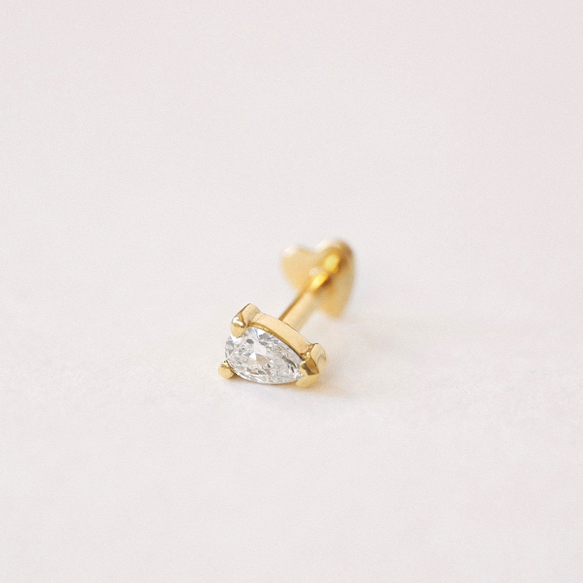 Piercing Gota em ouro amarelo 18k com diamante lapidação gota fotografado sobre fundo off-white.