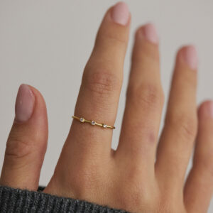 Modelo usando Anel Trio em ouro 18k com três diamantes.