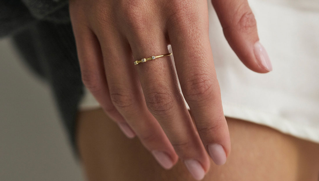 Modelo usando anel em ouro 18k com três diamantes alinhados.