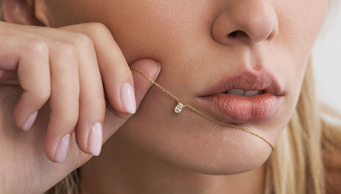 Modelo segurando colar solitário em ouro 18k com diamante em lapidação oval.