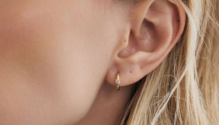 Modelo usando argolinha Mini Huggie em ouro 18k com diamante.