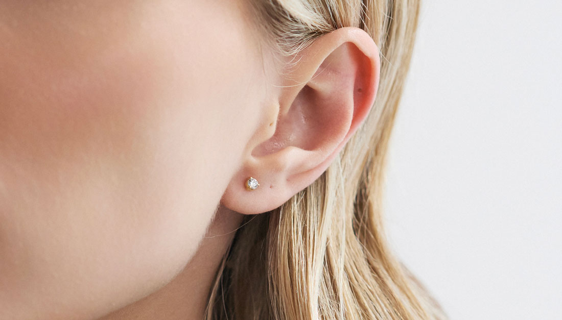 Modelo usando brinco stud em ouro 18k com diamante de 10 pontos.
