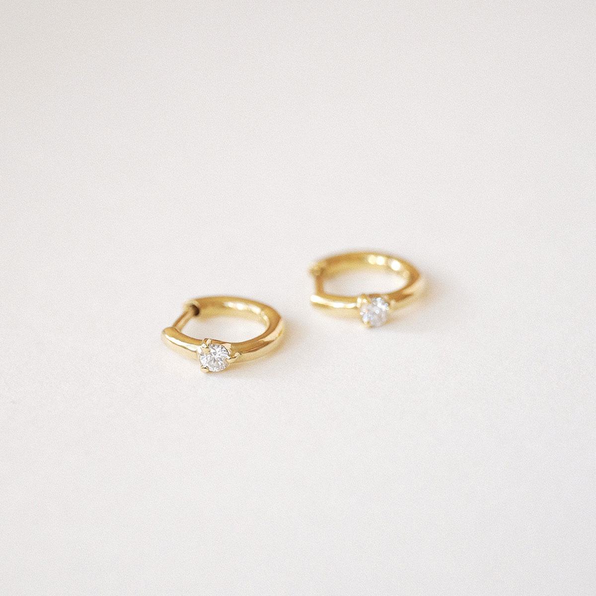 Close do Brinco Huggie Ponto em ouro 18k com diamante.