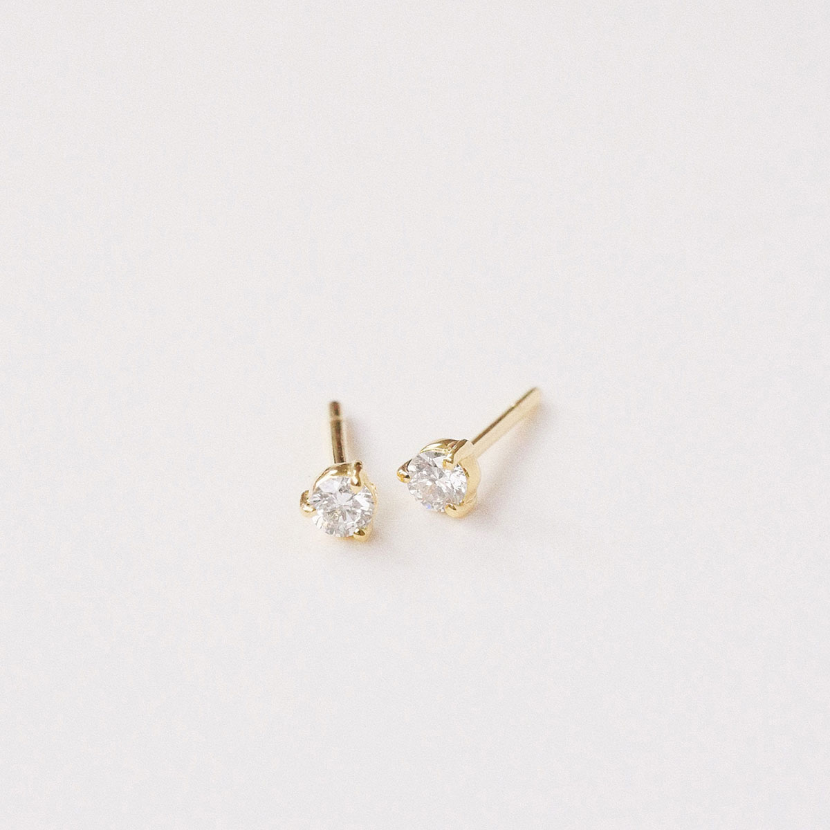Par de brincos stud em ouro amarelo 18k com diamantes de 10 pontos.
