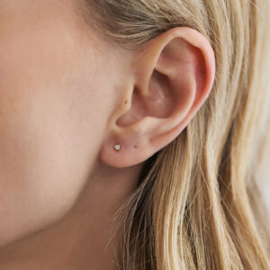 Modelo usando brinco stud de diamante de 2 pontos em close.