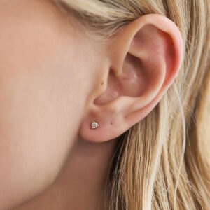 Close do brinco stud de diamante de 5 pontos em ouro 18k na orelha.