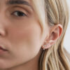 Modelo usando Ear Jacket Dot em ouro 18k com diamante combinado a um brinco stud de diamante redondo.