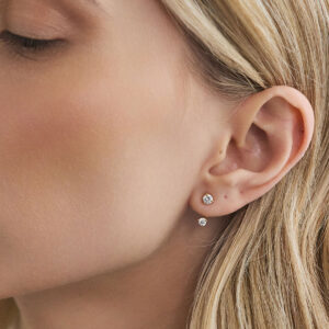 Detalhe do Ear Jacket Dot em ouro 18k com diamante usado junto a um brinco stud de diamante.