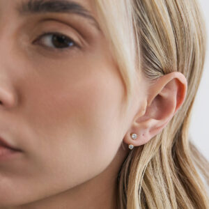 Modelo usando Ear Jacket Dot em ouro 18k com diamante combinado a um brinco stud de diamante redondo.
